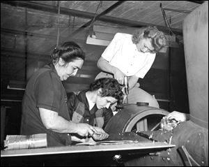 1945: Angela Durieux, Rossford, sits astride one of the robombs produced at the Willys-Overland Motors Inc. plant in Toledo, while Viva Hatt, Lottie Myskinski, and Agnes Mack (hands at right) of Toledo, work on assembling this war weapon.
