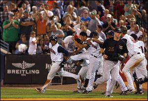 Toledo's Argenis Diaz, left, is chased by teammates after he drove in the winning run in the 11th inning to beat Louisville last night. Diaz's fourth hit of the game scored Ben Guez from third base.