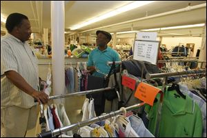 Fred Price, right, thanks Ronald Coleman for a parking courtesy as they shop at Next-to-New Shop at Trinity Church in downtown Toledo. One of the nice aspects of shopping in a thrift shop, Coleman says, is that customers are more courteous and more pleasant. Proceeds from the shop go to local ministry partners. 