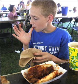Maumee resident Alex Turner, 13, licks his fingers after eating a pulled pork sandwich.
