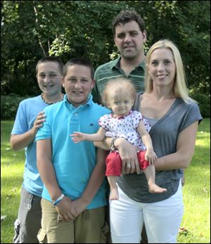 The Blade/Lisa BernheimHeather Kudzia holds her daughter, Carly, 14 months, who has progeria. With them are twins Garret, left, and Grant, 12, and the children's father, Ryan Kudzia.