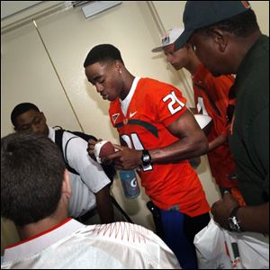 University of Miami Hurricanes defensive back Brandon McGee (21) signs autographs for fans at the Broward County Convention Center in Fort Lauderdale, Fla. For the first time, a Miami player is speaking out about the scandal that has rocked the Hurricanes' football program and sparked an NCAA investigation. 