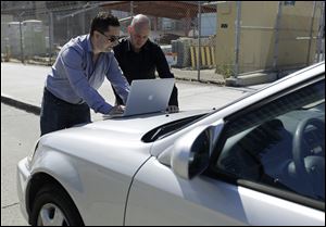 Security consultants Don Bailey, left, and Mathew Solnik, right, with iSEC Partners, demonstrate with a computer how they force cars with certain alarm systems to unlock their doors and start their engines by sending them text messages.