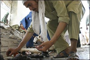 Pakistani villagers collect ball bearings after a suicide bombing at a mosque in Pakistani tribal area of Ghundi Friday.
