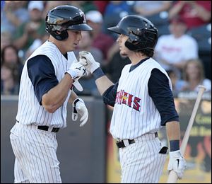 The Mud Hens’ Andy Dirks, left, is congratulated by Will Rhymes after hitting a home run in the fifth inning at Fifth Third Field.