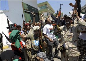 Libyan rebel fighters gesture at the former female military base in Tripoli, LIbya, Monday. Libyan rebels claimed to be in control of most of the Libyan capital on Monday after their lightning advance on Tripoli heralded the fall of Moammar Gadhafi's nearly 42-year regime.