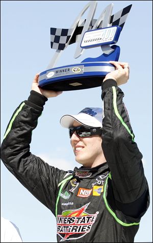 Kyle Busch holds up his trophy after winning the Pure Michigan 400 at Michigan International Speedway.