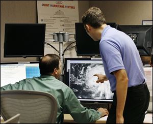 Hurricane Specialists at the National Hurricane Center Dan Brown left, and Eric Blake right, review the track and intensity of Hurricane Irene on Tuesday, Aug. 23, 2011, in Miami.