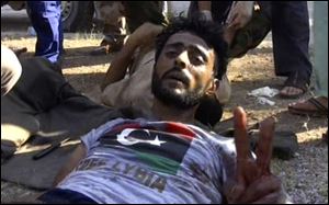 An injured rebel fighter gives the victory sign Tuesday after fighting just outside the compound of Moammar Gadhafi in Tripoli, Libya.