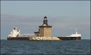 The freighter American Mariner sails behind the Toledo Harbor Lighthouse in the shipping lane. The lighthouse will welcome its first visitors Saturday.