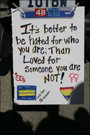 A sign hangs from the license plate of a motorcycle that led Saturday’s parade in Toledo.
