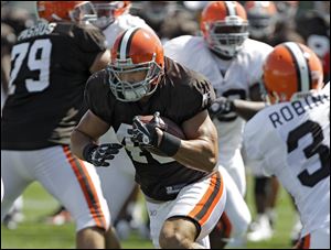 Cleveland Browns running back Peyton Hillis, center, runs the ball during practice at the NFL football team's training camp in Berea, Ohio Monday, Aug. 29, 2011. Hillis, who appears on the cover, Madden 12, passed out advance copies of the popular football video game, in Cleveland's locker room.