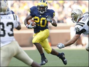 University of Michigan running back Michael Shaw #20 gets by Western Michigan University linebacker Austin Pritchard #35 during a game in 2009.