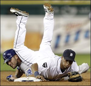 Tigers second baseman Ramon Santiago (39) lands on the Royals' Mike Moustakas after throwing to first base to complete a double play on a Salvador Perez ground ball in the ninth inning.