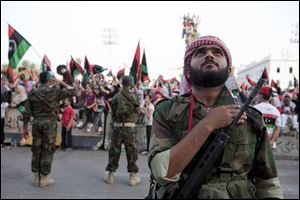 A rebel guard listens to the new national anthem during a rally in the former Green Square, now called Martyrs’ Square, in Tripoli, which is firmly in rebel hands. However, Seif al-Islam, Moammar Gadhafi’s son, vows to retake the capital city.