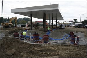 Workers from Lawrence Building Corp., in Ft. Wayne, Ind., work on what will be a Kroger gas station at the corner of Monroe and Secor.
