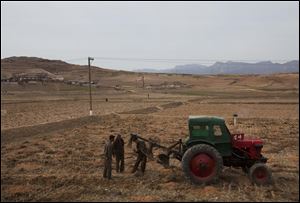 Men check a plow and tractor in a field along the highway near the southern city of Kaesong, south of Pyongyang, North Korea, earlier this spring.