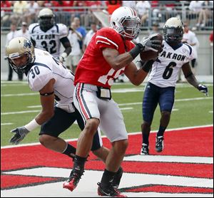 Ohio State's Devin Smith (15) catches a touchdown pass against Akron defenders L.T. Smith (30) and Manley Waller (6) during the fourth quarter.