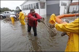 Workers hand off sandbags to to to stop flooding waters from Bayou Barataria encroaching on homes and businesses in the aftermath of Tropical Storm Lee in the town of Jean Lafitte, La., just outside New Orleans on Saturday.