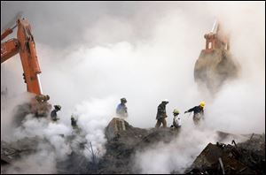Firefighters make their way over the ruins of the World Trade Center through clouds of smoke at ground zero in New York, in this Oct. 11, 2001 file photo.