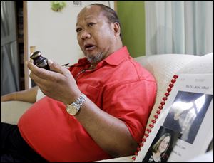 Rudy Abad sits beside the picture of his late wife Marie Rose Abad, who died during the Sept. 11, 2001, attacks on the World Trade Center,  in his home in Tagaytay City, south of Manila, Philippines. He is holding a small urn in which he keeps a portion of his wife's ashes. Unlike many victims of the 2001 attacks who are remembered mostly by their family and friends, Marie Rose Abad's legacy lives on half-way around the world in a once-notorious Manila slum now turned into a tidy village that carries her name. 