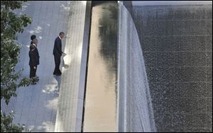President Barack Obama, foreground, runs his hand along the names on the Sept. 11 memorial as former President George W. Bush, Laura Bush and Michelle Obama look on as they visit the memorial Sunday.