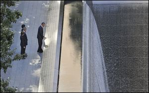 President Barack Obama, foreground, runs his hand along the names on the Sept. 11 memorial as former President George W. Bush, Laura Bush and Michelle Obama look on as they visit the memorial Sunday.