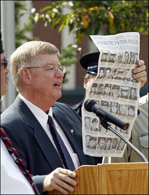 Mayor Craig Stough holds up a page of The Toledo Blade honoring  36 servicemen who have died that have ties to northwest Ohio and southeast Michigan during a remembrance ceremony to mark the 10th anniversary of the terrorist attacks on Sept. 11, 2001 at River Centre Park in Sylvania.