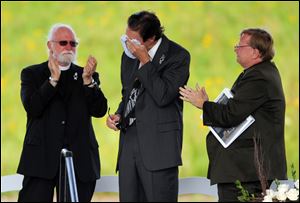 Wally Miller, Somerset County coroner, wipes his eyes as he is applauded during the service. Mr. Miller, who read a litany of remembrance, is flanked by the Rev. Paul Britton and the Rev. Robert Way.
