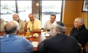 Rabbi Moshe Saks, his finger raised, tells a story to members of the coffee klatch, with Sanford Stein at his left, Leon Williams at his right, and Howard Rosenbaum at the table's end.