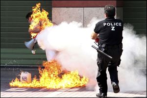 A police officer uses a fire extinguisher as a man sets himself on fire outside a branch of Piraeus bank in the northern port city of Thessaloniki, Greece, Friday. It was a third attempted self-immolation by the former small business owner, who says he was ruined after taking a series of bank loans. The 56-year-old was hospitalized with non life-threatening chest burns.