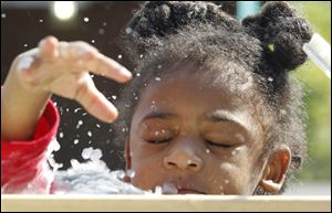 Ahmad Golladay, 2, gets splashed with water after he drops his fossil in a bucket of water while cleaning it.