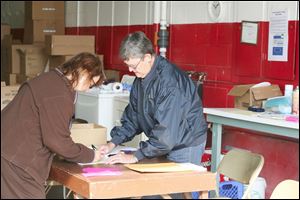 Barb Engle, right, registers Barb Frankforther for the food distribution program at the old fire hall in Perrysburg Township. Ms. Frankforther was picking up for relatives.