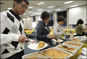 Nico Covarrubias, left, of Toledo, and Beatrice Moreno of Holland help themselves to the Hispanic-themed buffet.