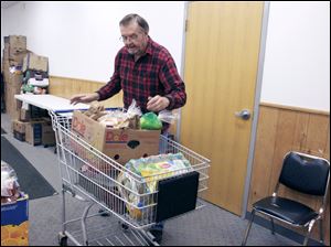 Walt Wilkerson, a volunteer at Sylvania Area Family Services, organizes food into a cart to distribute to clients of the agency's assistance program.