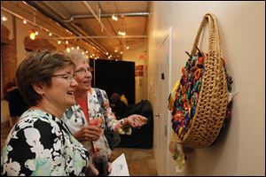 Anastasia Hanson, left, and Lois Whiteman look at a beach bag decorated with condoms during the Planned Parenthood of Northwest Ohio's third annual Art of Prevention gala at Space 237 Galleries in Toledo.