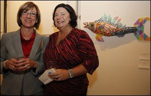 Janine Avila, left, and Lisa Guest Perks pause in front of a fish made of condoms.
