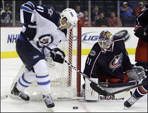 The Blue Jackets' Mark Dekanich, right, makes a save against Winnipeg Jets' Jason Jaffray in the opening preseason game between the two teams in Columbus.