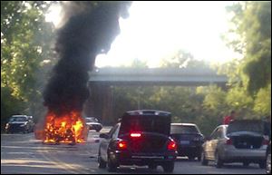 The vehicle in which local attorney Erik Chappell and two boys were traveling on Elm Avenue near I-75 in Monroe burns after an explosion Tuesday, in this image from the Monroe Evening News.