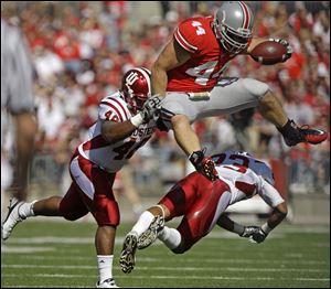 Ohio State's Zach Boren, top, hurdles Indiana's Adrian Burks, right, and Leon Beckum during the first quarter of an NCAA college football game Saturday, Oct. 9, 2010.