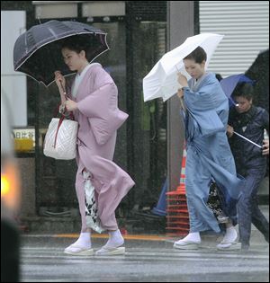 Two women in kimonos make their way through Tokyo's Ginza shopping area Wednesday as powerful Typhoon Roke lashes central Japan with heavy rains and sustained winds of up to 100 mph.