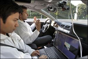 It's hands off for Miao Wang, left, and Tinosh Ganjineh as the computer-driven car winds  around Berlin. The car can run without anyone on board on a testing ground.