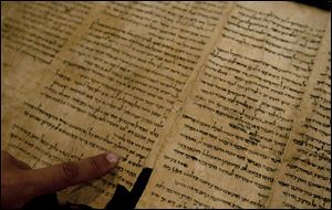 An Israel Museum worker points at the word 'Jerusalem' written in a part of the Isaiah Scroll, one of the Dead Sea Scrolls, inside the vault of the Shrine of the Book building at the Israel Museum in Jerusalem. Five scrolls went online Monday.