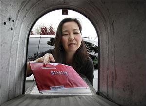 Carleen Ho poses with a Netflix movie she is picking up from her mail box in Palo Alto, Calif.