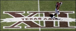 In this photo taken Saturday Texas A&M wide receiver Nate Askew (9) walks across a Big 12 logo on Kyle Field.