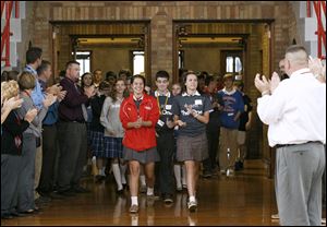 Central Catholic senior Chelsie Jagodzinski, left, and junior Kayle Mustafaga, right, lead eighth graders from Joan of Arc, Regina Coeli, and St. John the Baptist into a pep rally Wednesday after a tour of Central Catholic High School during  