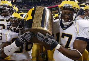 Michigan leads series 70-24-3 all-time in nation's oldest trophy game. Michigan players hoist the 