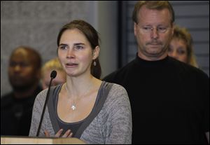 Amanda Knox talks to reporters as her father, Curt Knox, right, stands behind her Tuesday, Oct. 4, 2011, in Seattle. Knox was freed Monday after an Italian appeals court threw out her murder conviction for the death of her British roommate, Meredith Kercher.