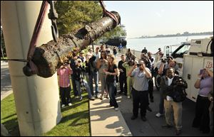 A large crowd photographs the last of five sunken cannons believed to be over 200 years old recovered from the Detroit River on Wednesday.