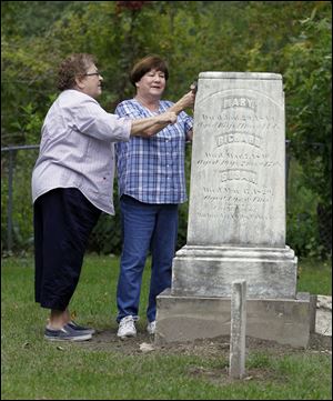 Dawn Pirolli, left, and Nancy Dusa clean the monument of Richard Peters and his daughters Mary and Susan in Wing Cemetery. Richard Peters founded Petersburg,